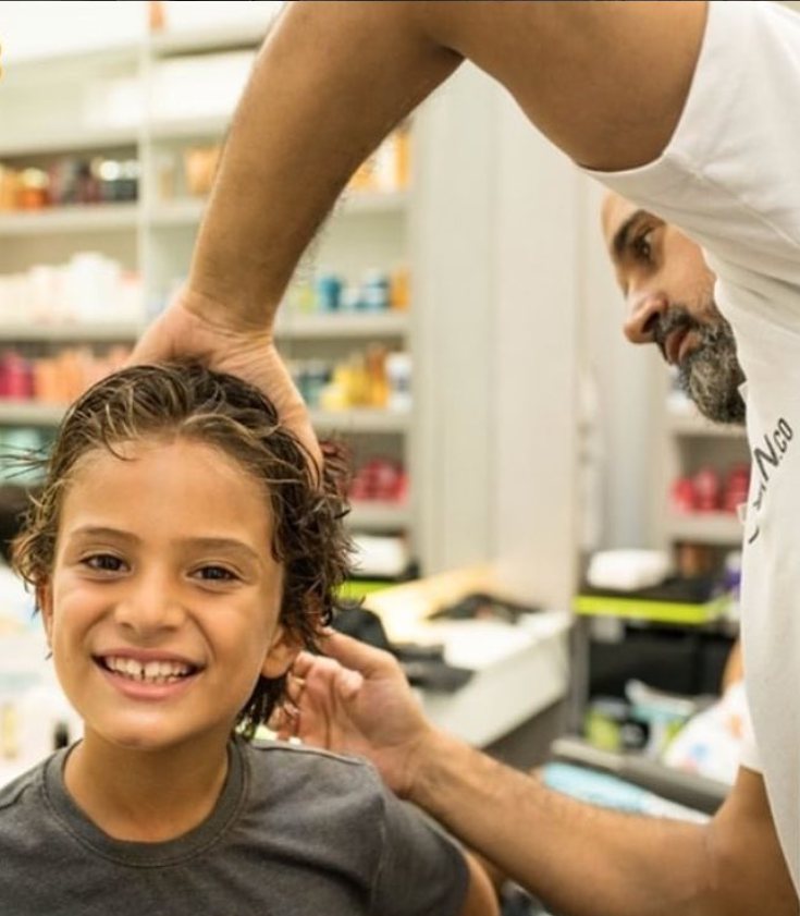 A smiling boy in the chair getting his haircut