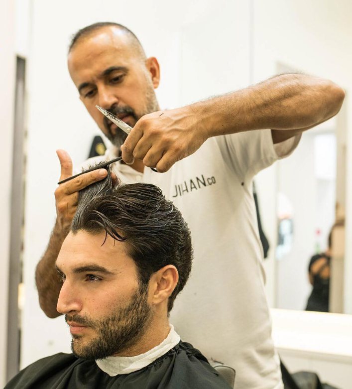 Barber finishing a scissor cut on a client with a full beard