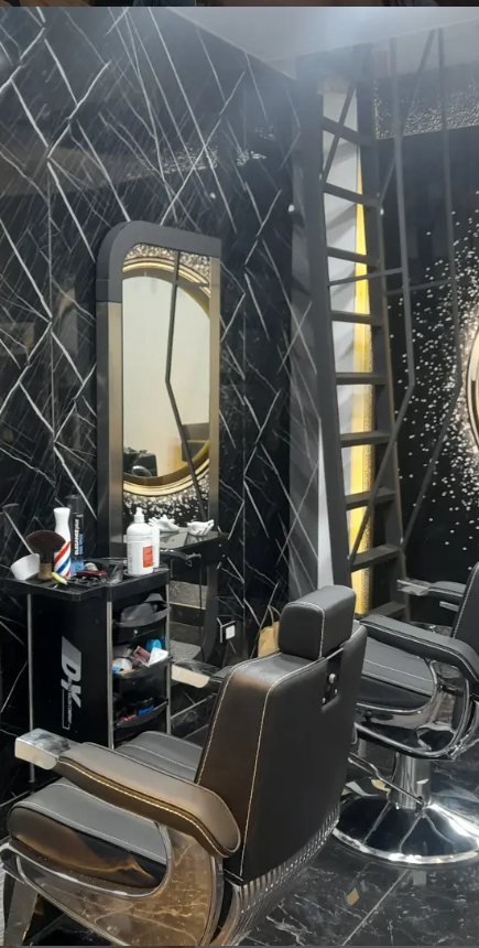 Leather barber chair facing a backlit mirror on the black marble wall